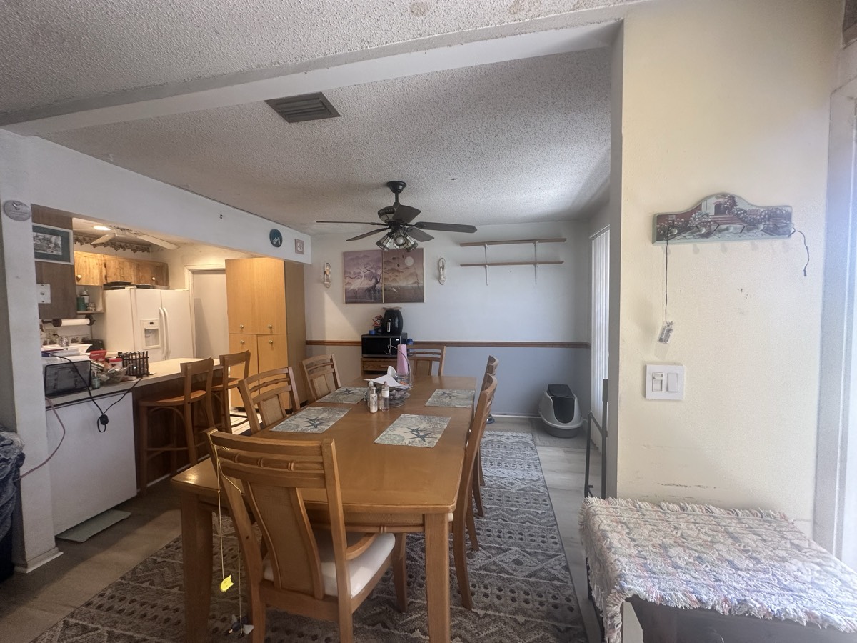 Original dated dining and living space with worn flooring and dark cabinetry