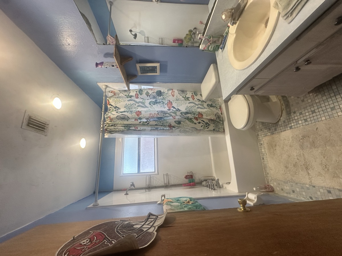 Original dated second bathroom with tub-shower combo and blue walls