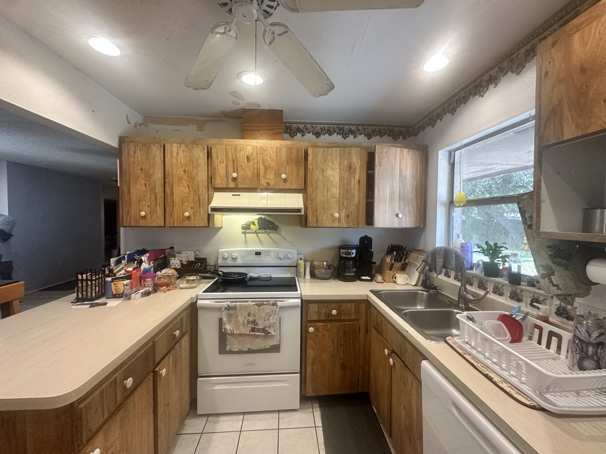 Dated kitchen with wood cabinets and worn countertops before renovation