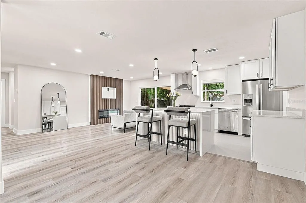 Same kitchen after renovation with white cabinets, quartz counters and new appliances